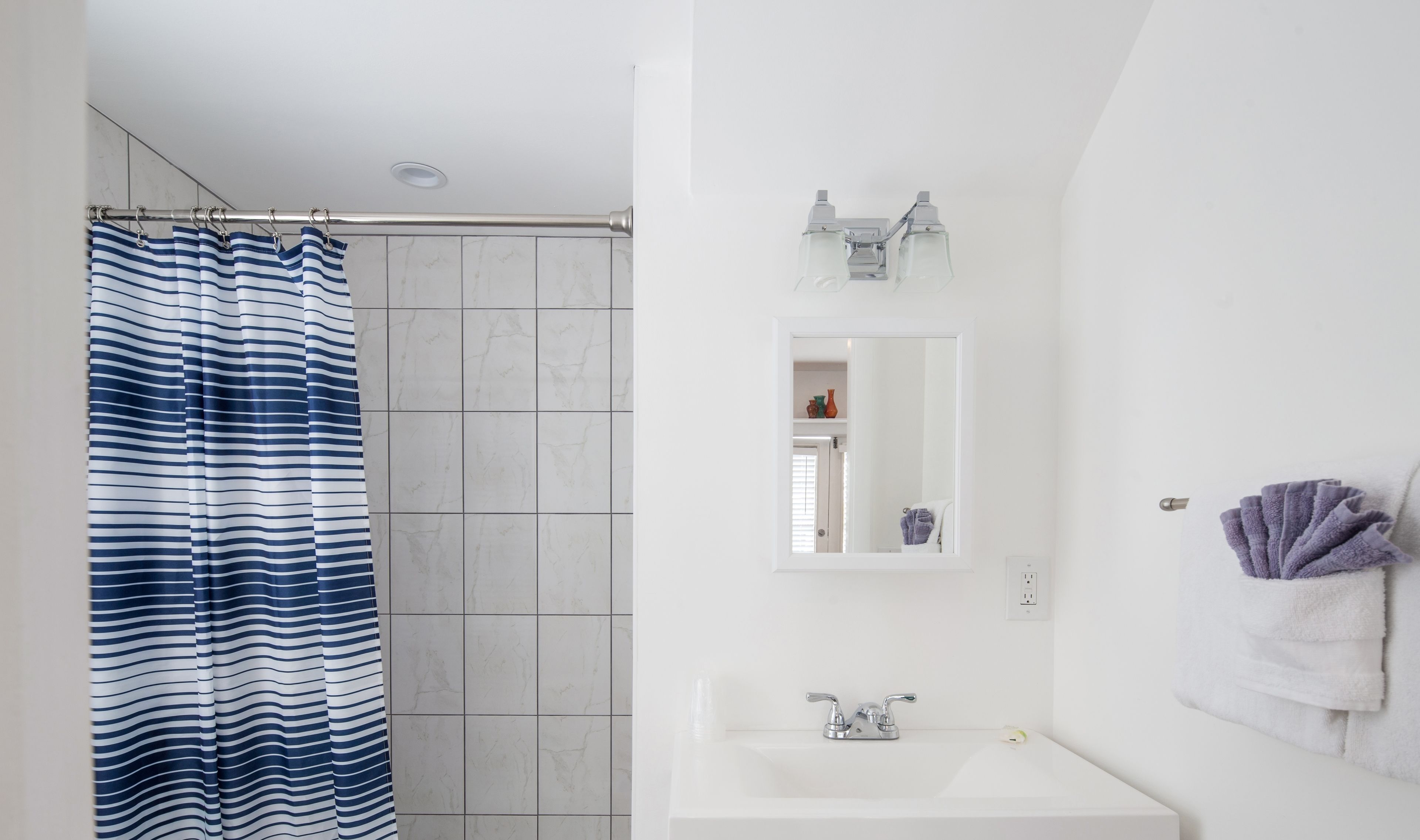 A bathroom with a white sink, a mirror, and a shower curtain.