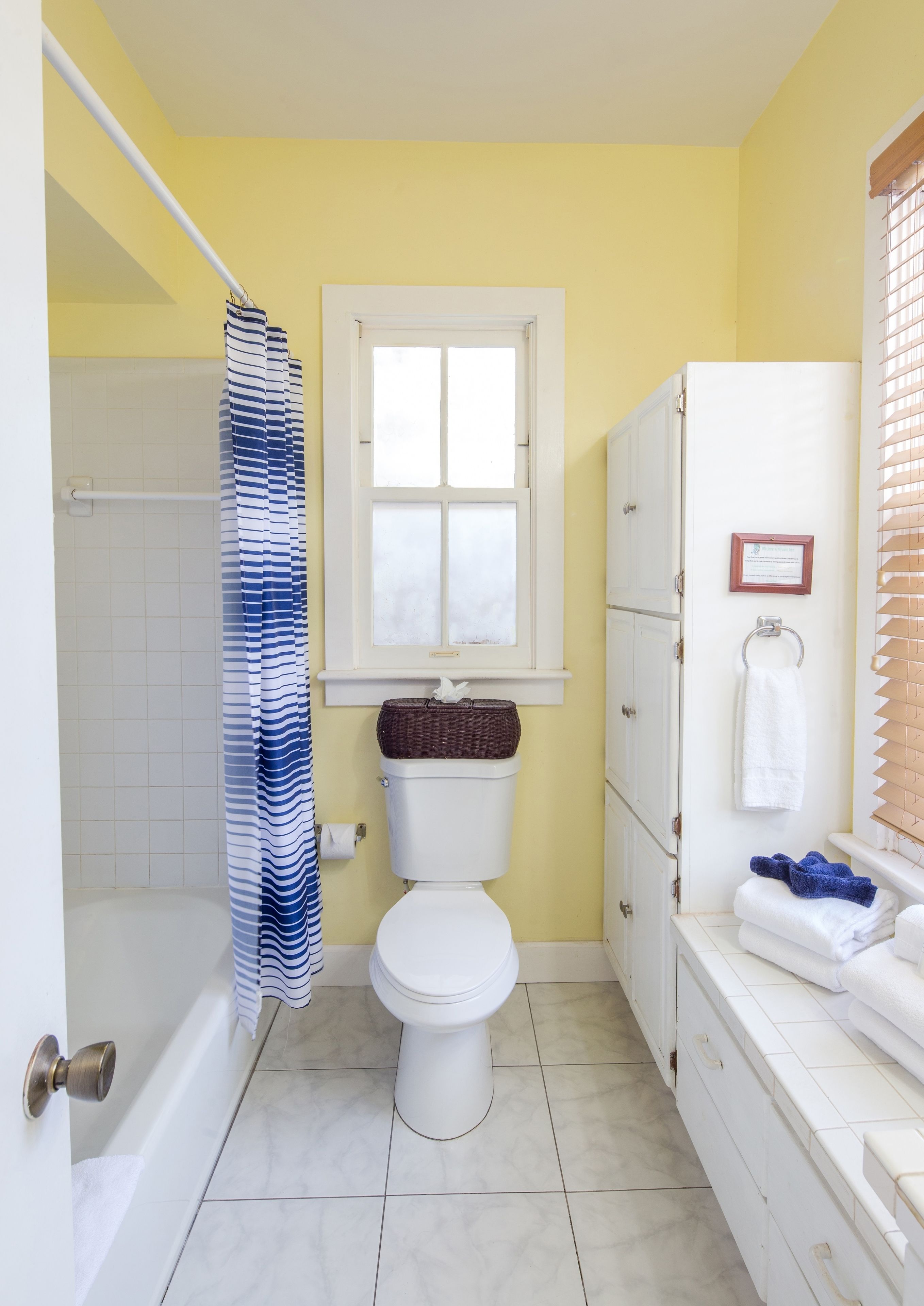 Un bagno con il water, una vasca, un tenda per la doccia, una finestra e un porta asciugamani.