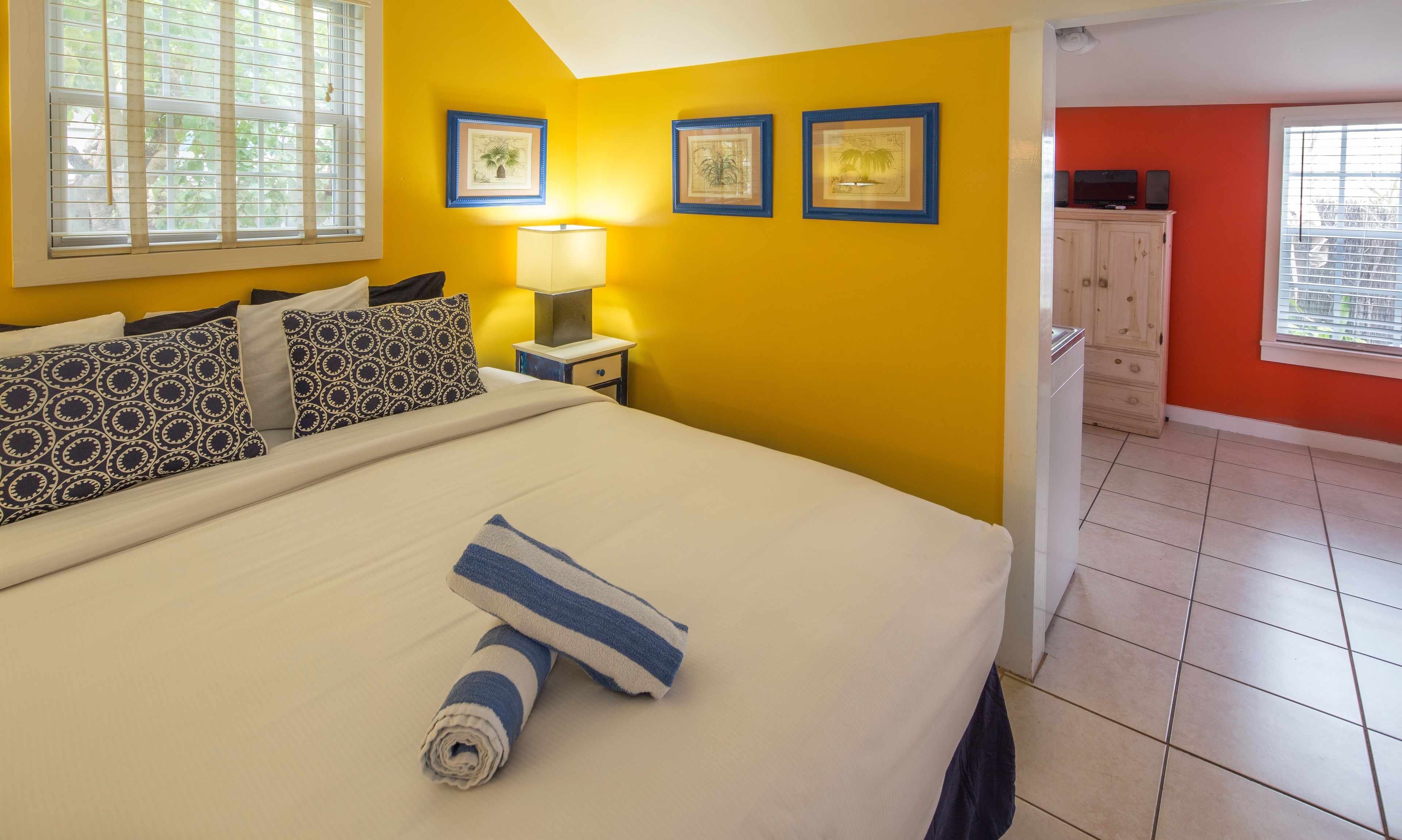 Una habitación de hotel con una cama, una mesita de noche con lámpara y cuadros en la pared.