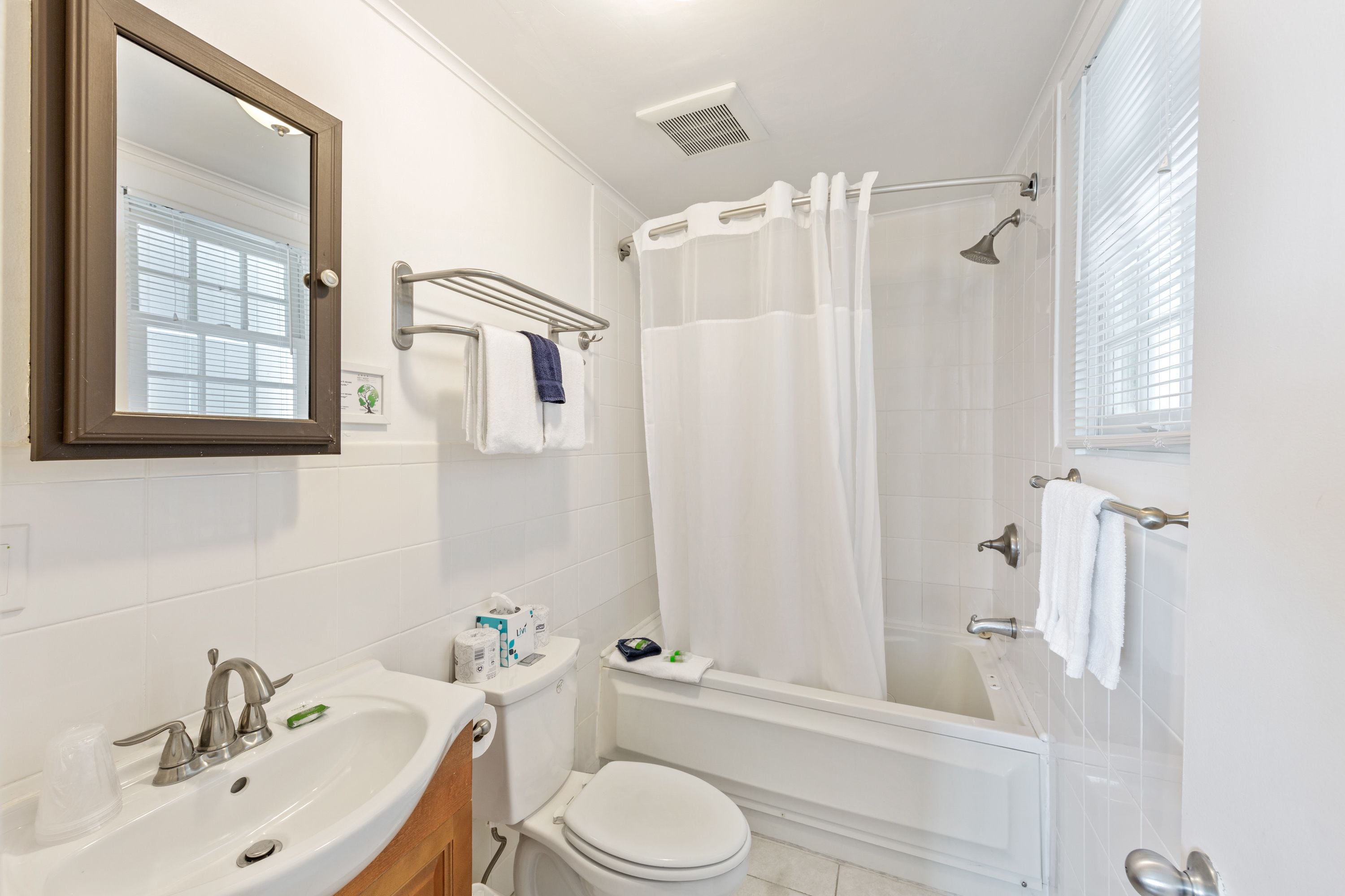 A bathroom with a white sink, toilet, and bathtub. There is a towel rack above the sink and a shower curtain over the bathtub.
