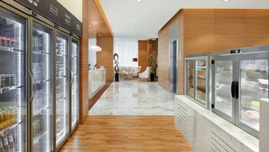 A modern hotel lobby with a wooden floor, glass display cases, and a seating area with white chairs.
