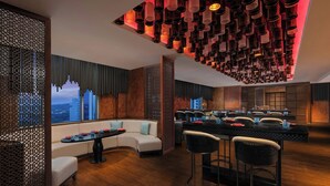 Een moderne bar met een gebogen bank, een ronde tafel en barstoelen.