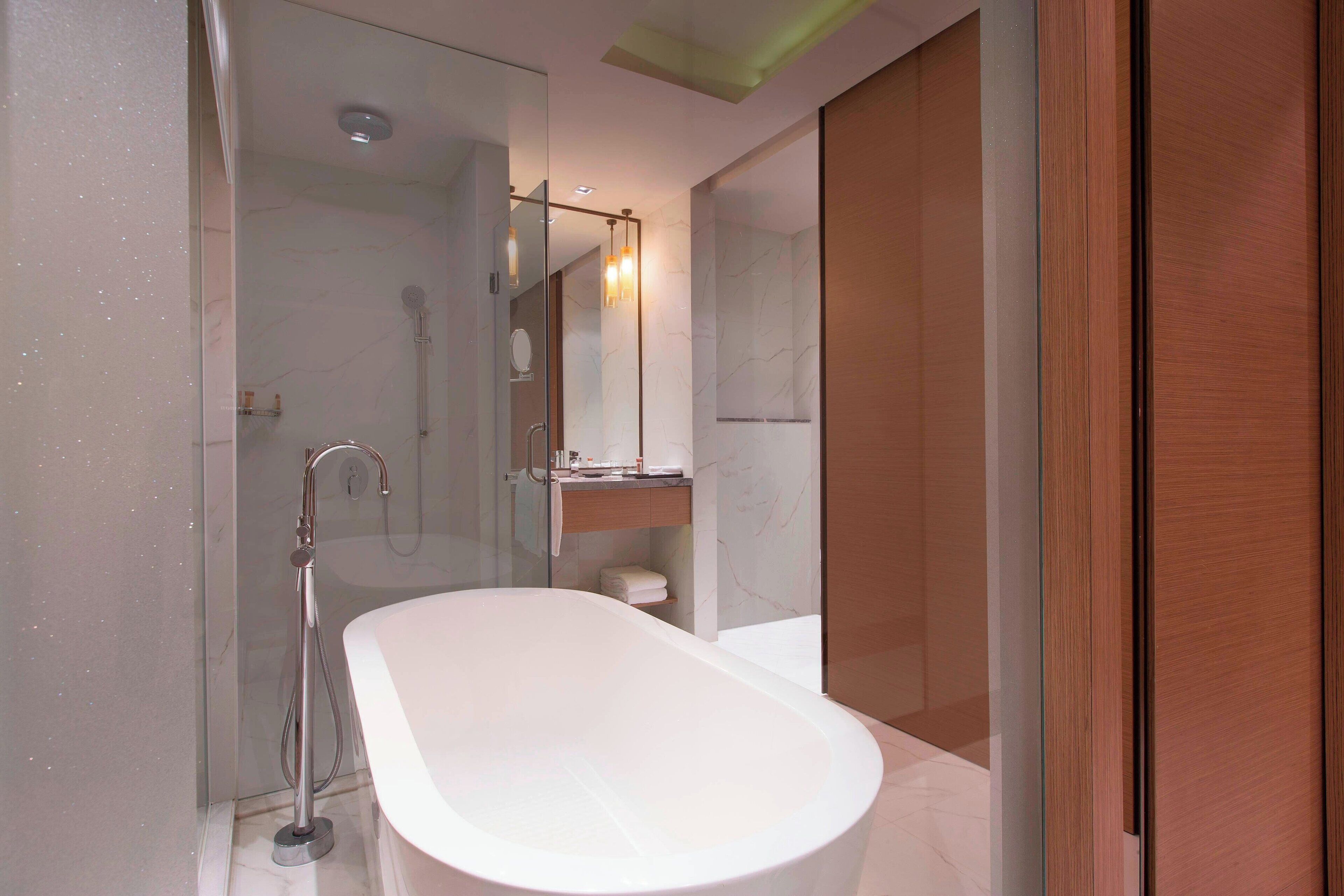 A modern bathroom with a freestanding bathtub, a glass-enclosed shower, and a wooden vanity.