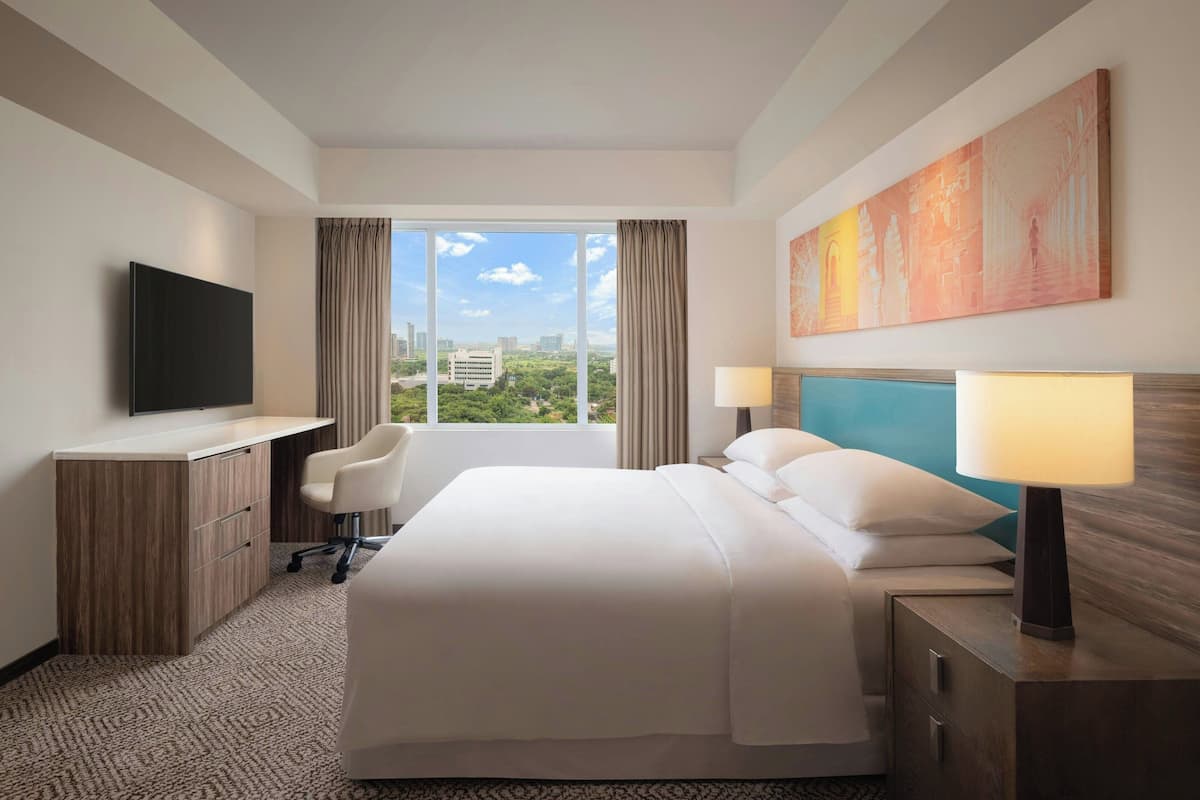 Ein Hotelzimmer mit Bett, Schreibtisch, Stuhl, Fernseher und einem Gemälde.
