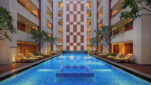 Een hotel met een centraal gelegen zwembad, meerdere verdiepingen en loungegedeeltes met ligbedden.