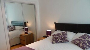 A bedroom with a bed, nightstands, a lamp, and a wardrobe. - Dreamhouse Apartments London (London)