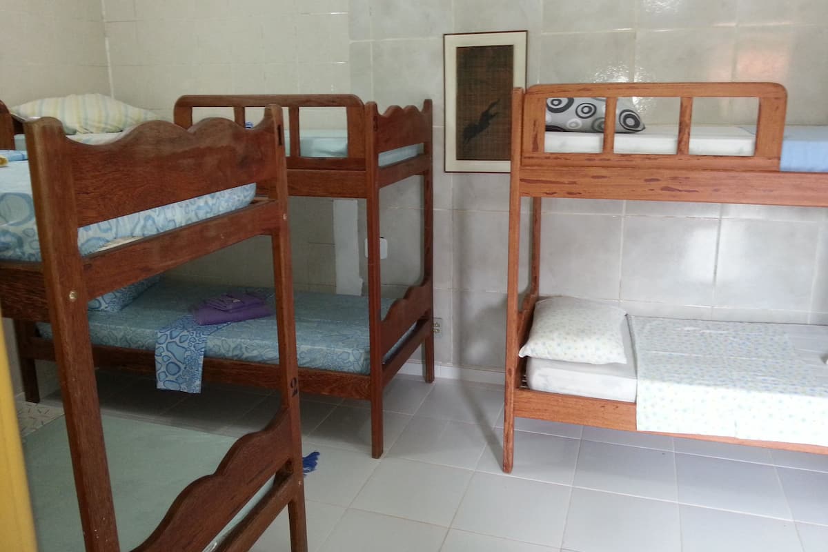 A room with two wooden bunk beds, a framed picture on the wall, and a tiled floor.