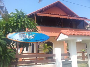 A hostel with a signboard, a tiled roof, and a wooden fence. - Itaúna Hostel (Saquarema)