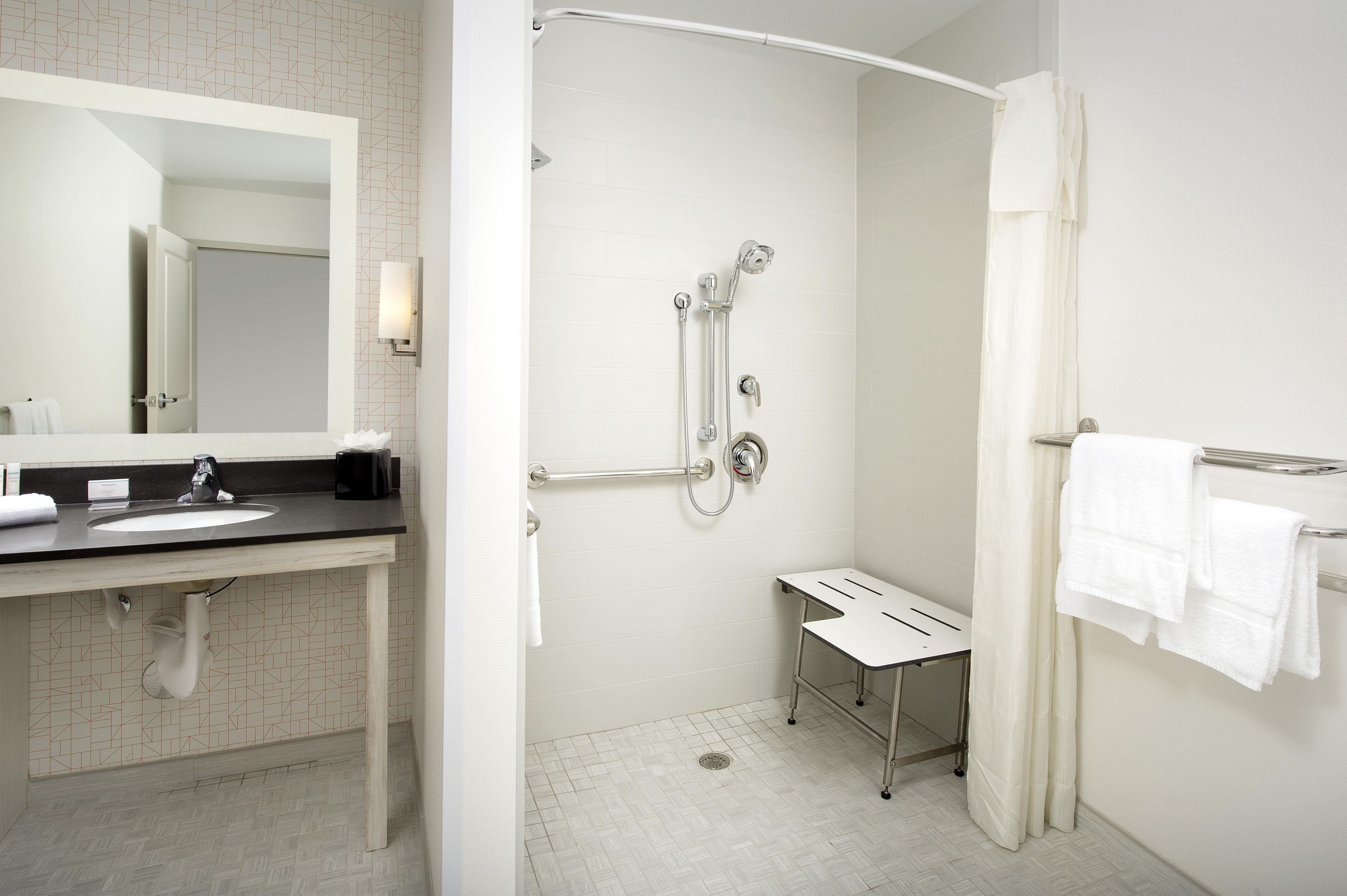 Une salle de bain moderne avec une douche, un lavabo et un miroir.