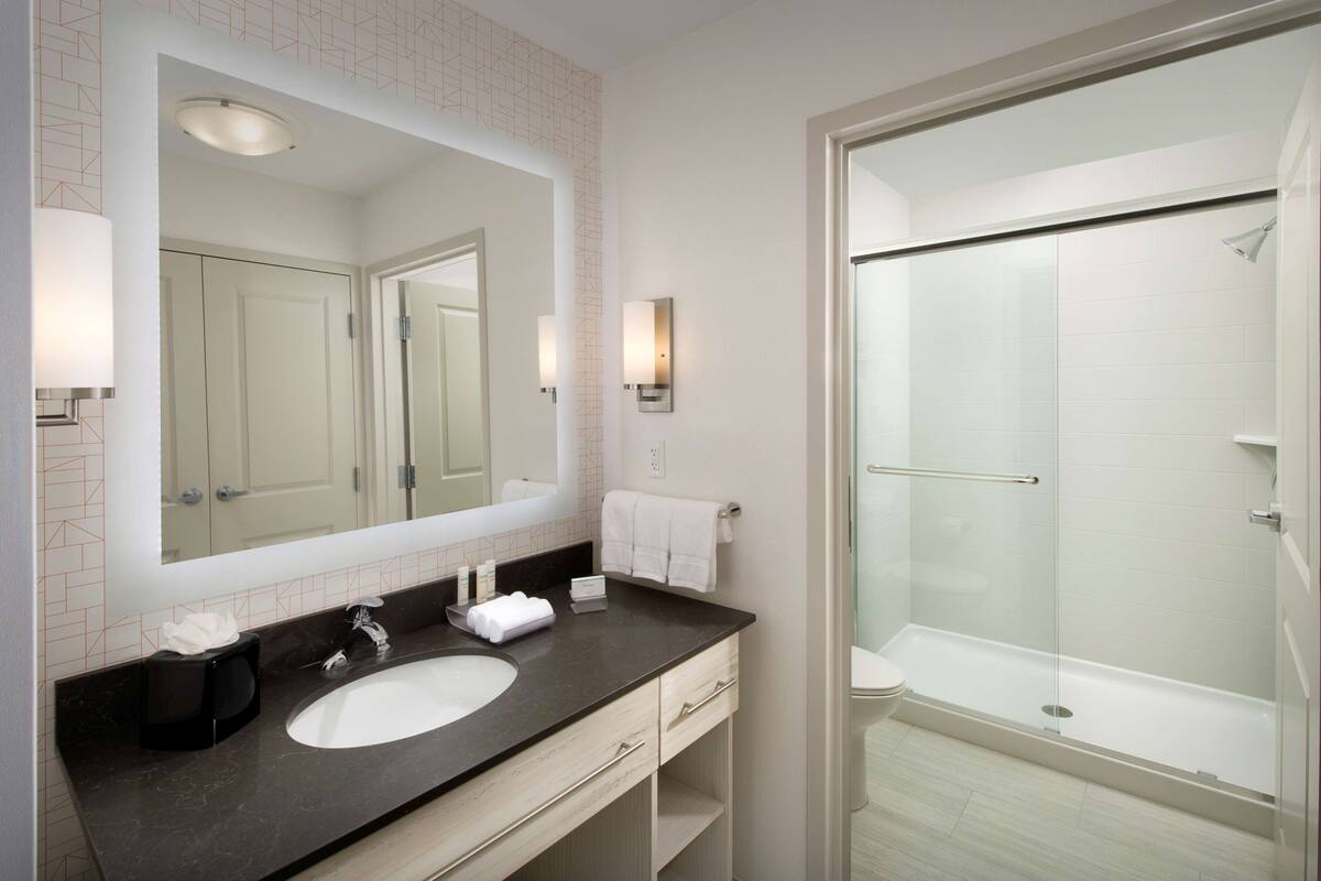 Een moderne badkamer met een grote spiegel, een wastafel en een douche met glazen wanden.