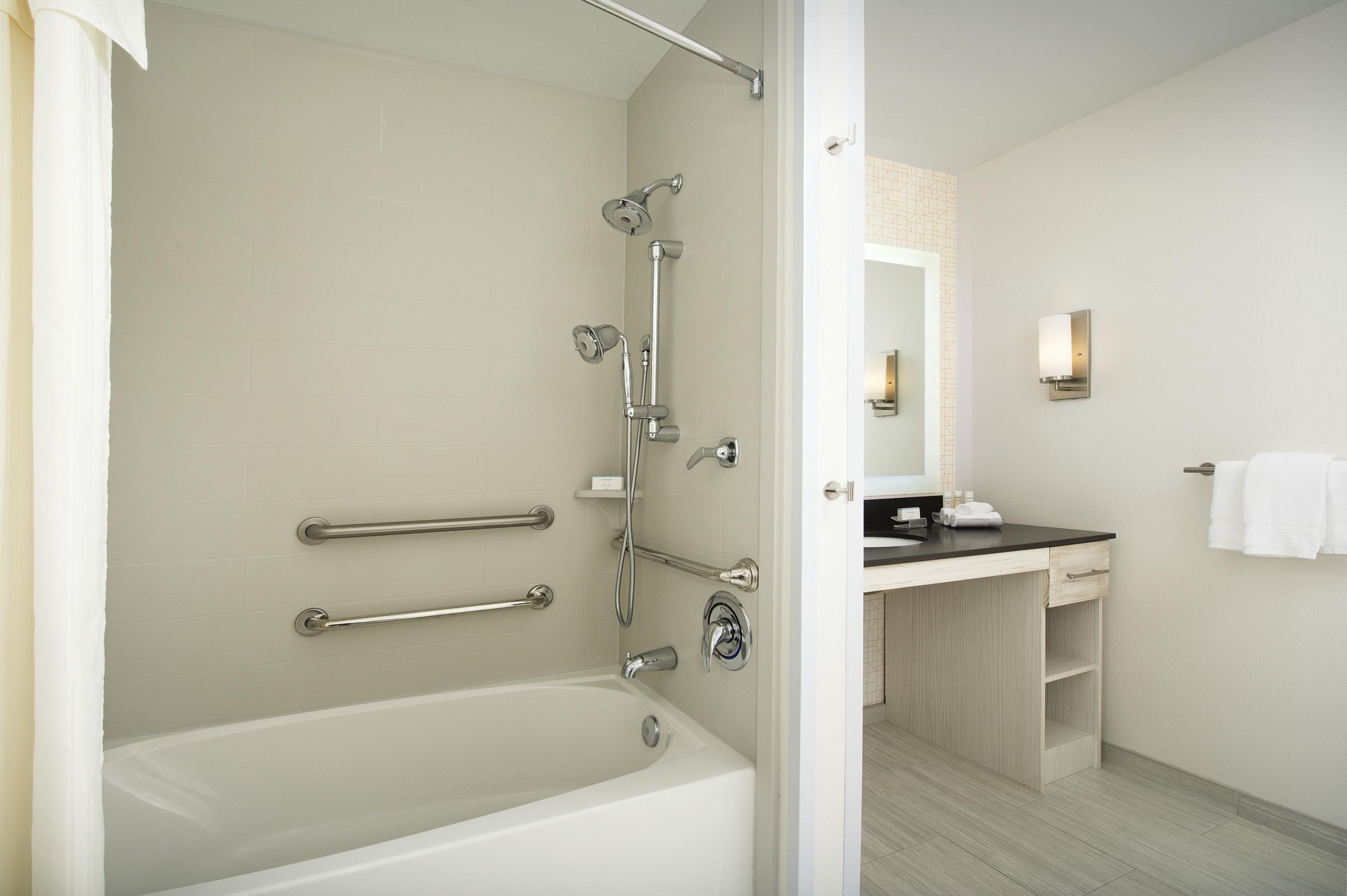 A bathroom with a bathtub, a shower with a handheld showerhead, a toilet, and a sink with a mirror.