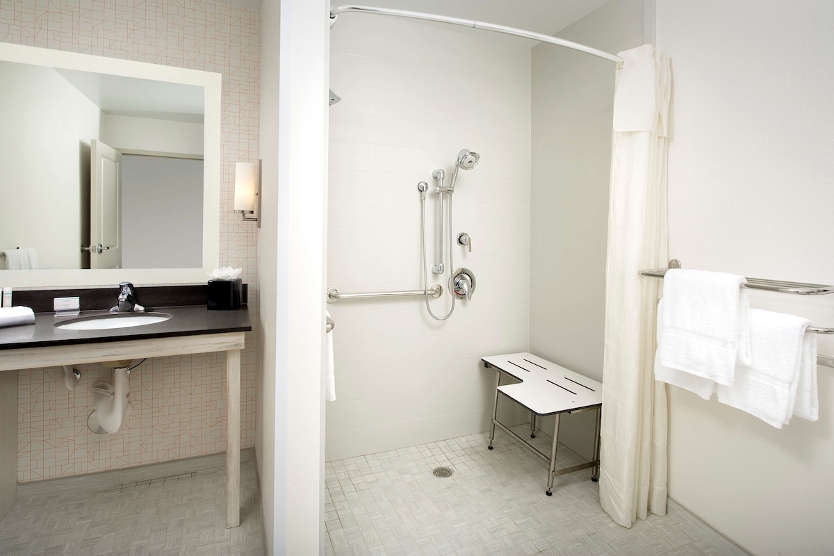 Une salle de bain moderne avec un lavabo blanc, un miroir et une douche.