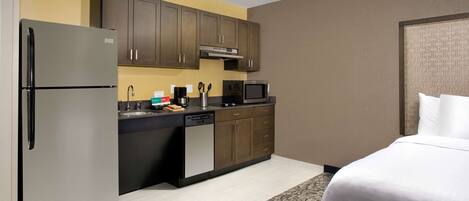 Une chambre d’hôtel compacte dotée d’une kitchenette, comprenant un réfrigérateur, un four à micro-ondes et un évier.