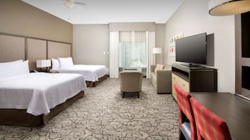 Une chambre d’hôtel avec deux lits, une télévision, un bureau et un petit coin salon.