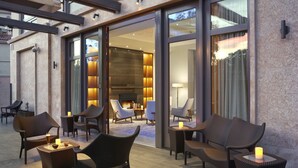 An outdoor seating area with wicker furniture and candles, leading to a well-lit interior with a fireplace and modern decor. - Clement Palo Alto – All-Inclusive Urban Resort (Palo Alto)
