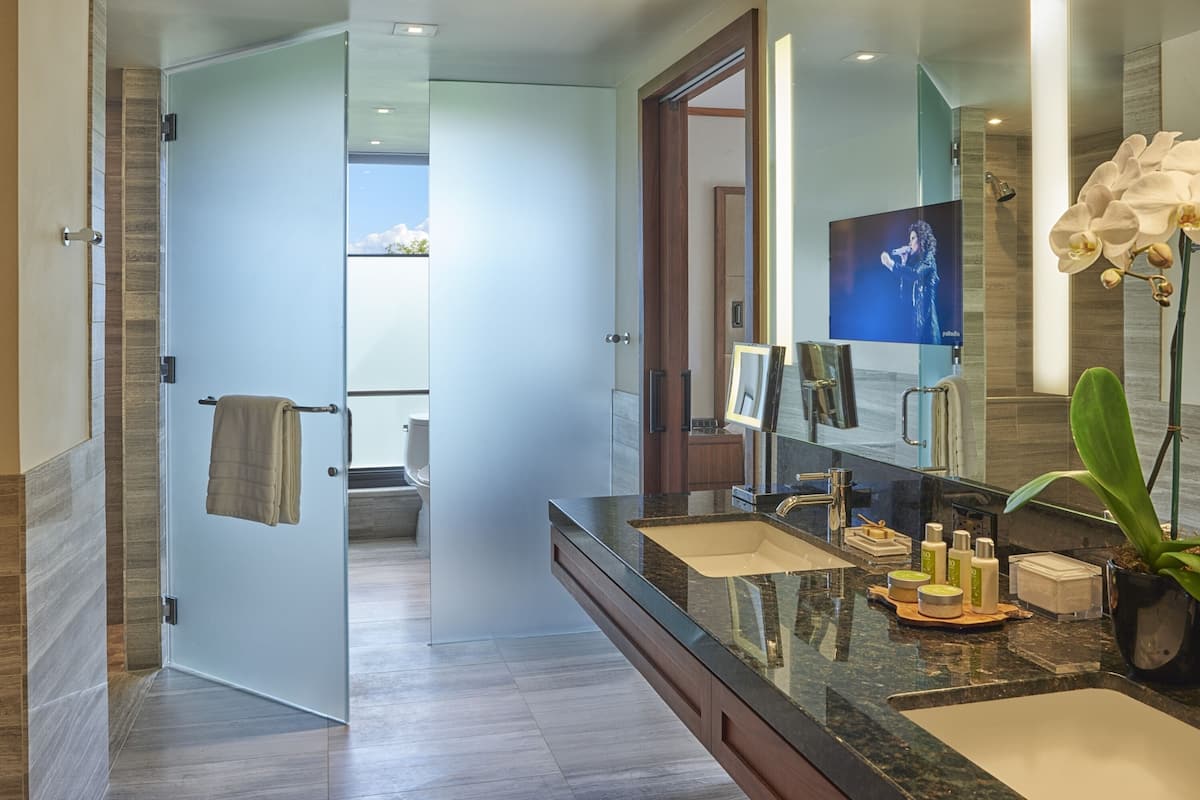 A modern bathroom with a large mirror, a vanity with a sink, and a shower area visible through an open door.