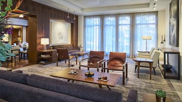 A spacious living area with a sofa, coffee table, and chairs, a dining area with a table and chairs, and a large window with curtains.