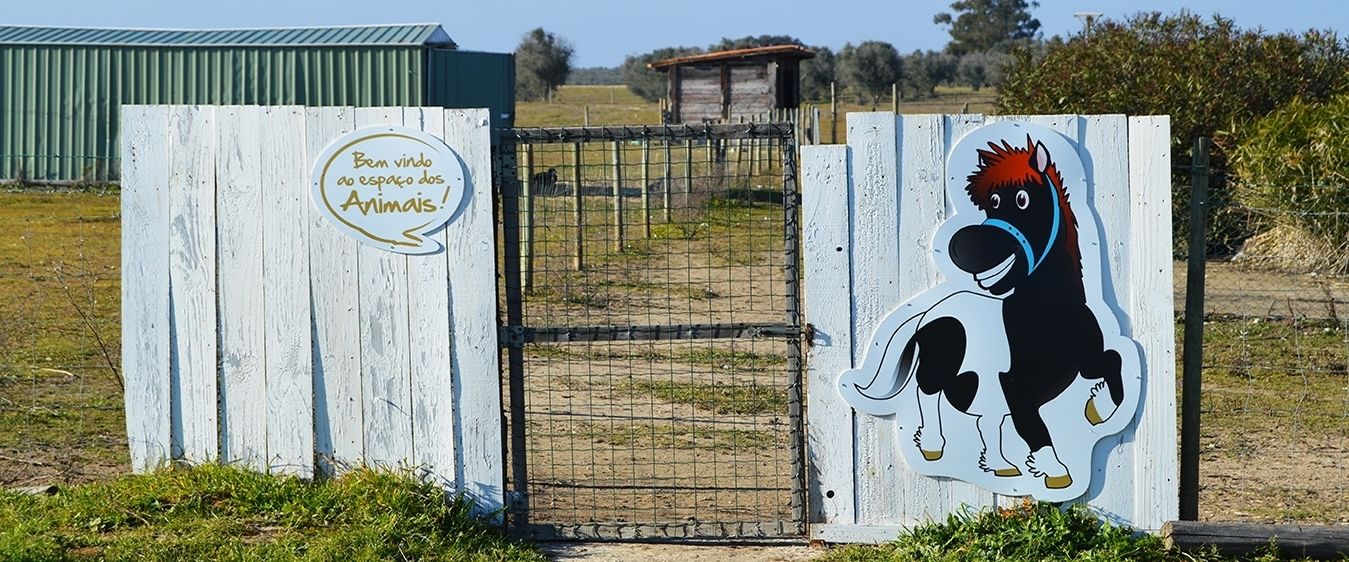 Un portón de madera con un caballo pintado y un letrero que dice 'Bem vindo ao espaço dos Animais!'