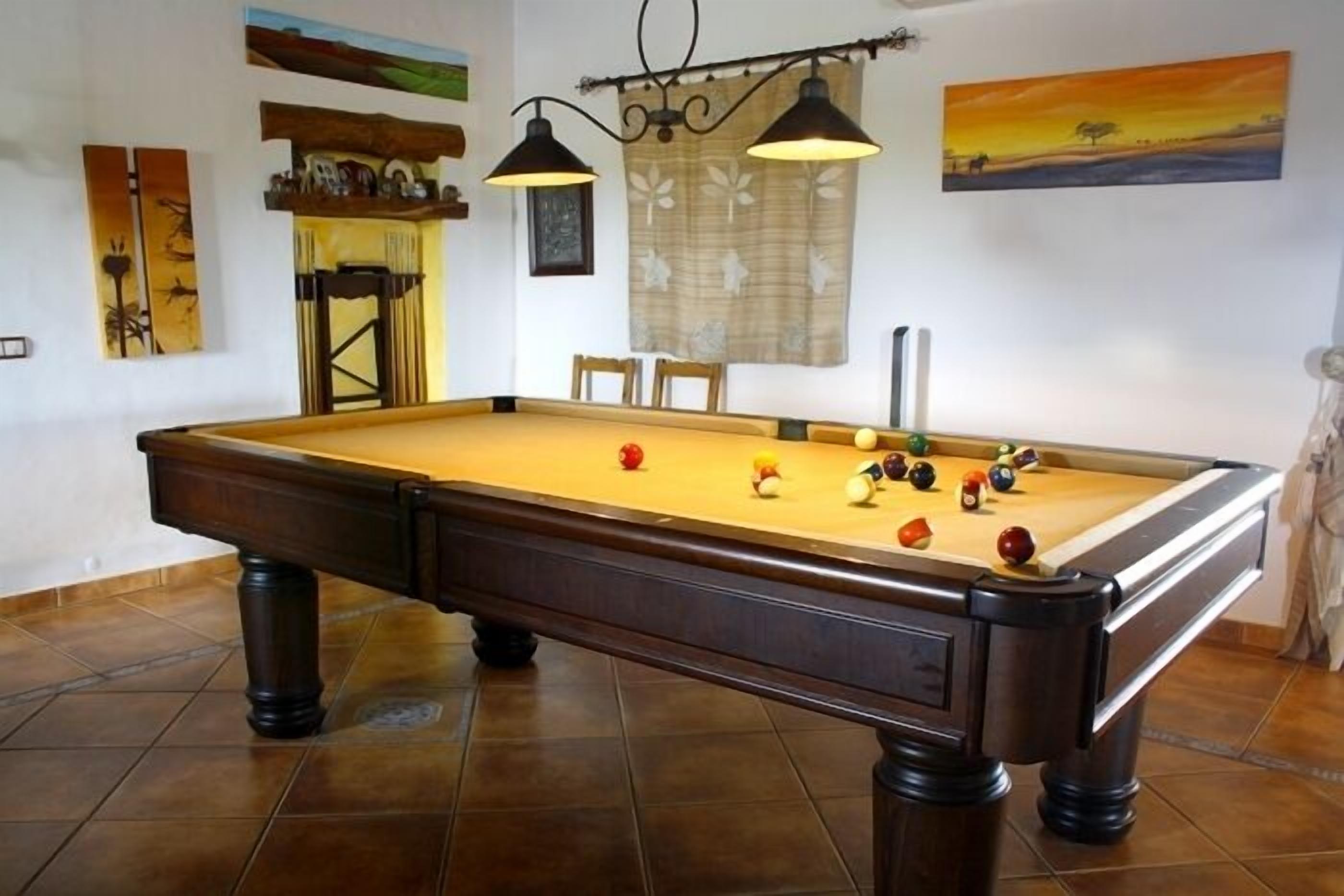 A pool table with balls, a lamp, and artwork on the walls.