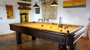 A pool table with balls, a lamp, and artwork on the walls.