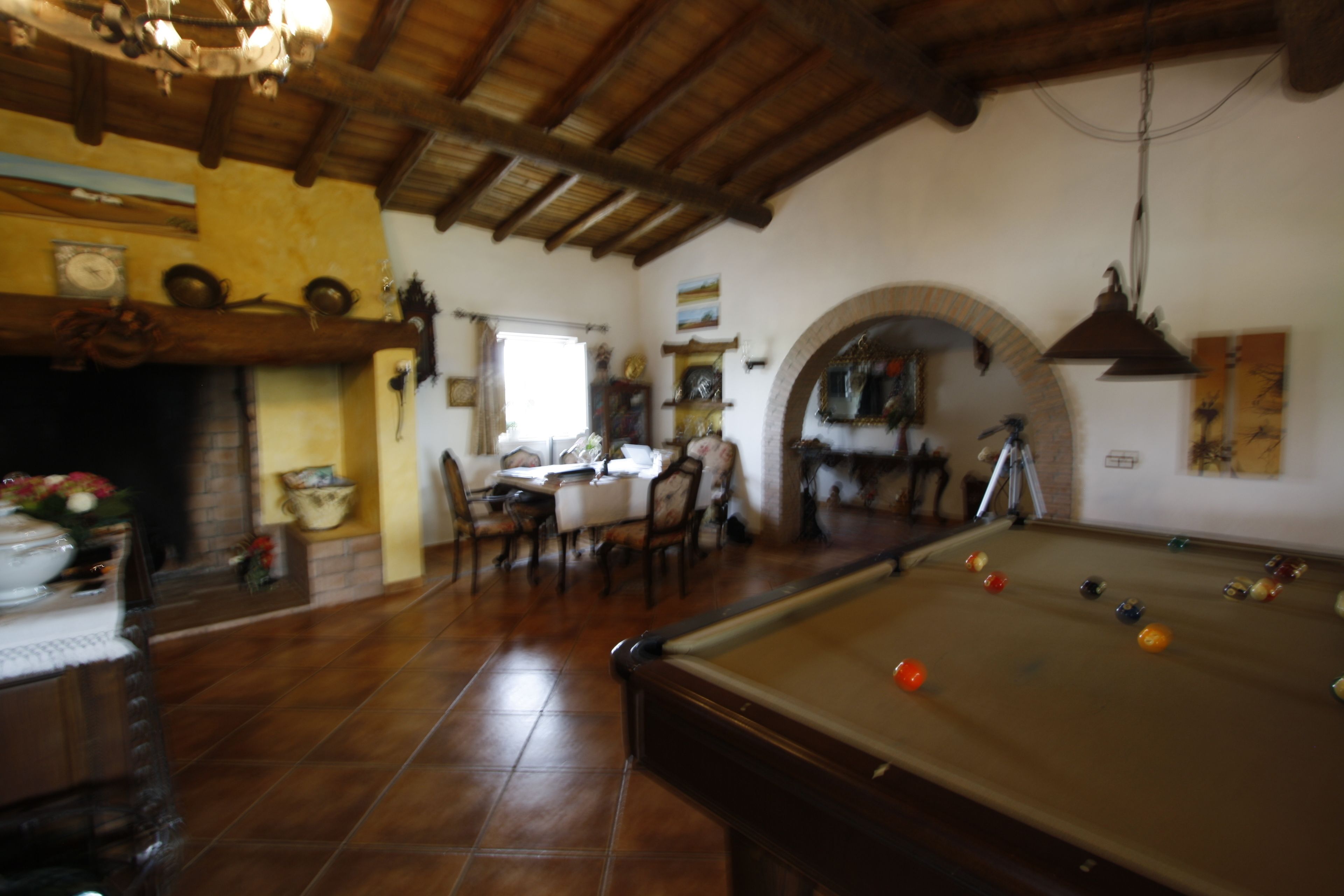 Una habitación acogedora con mesa de billar, vigas de madera y chimenea.