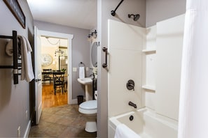 A bathroom with a bathtub, toilet, sink, and a mirror. - Asheville Cottages (Asheville)