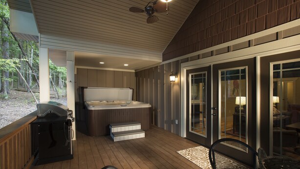 Un espacio al aire libre techado con jacuzzi, parrilla y asientos.