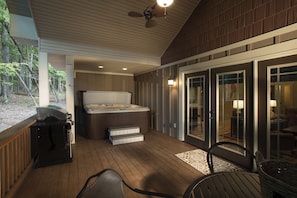 A covered outdoor area with a hot tub, grill, and seating. - Asheville Cottages (Asheville)