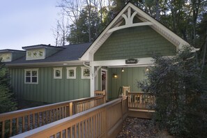 A green building with a sign reading "The Maple." It features a wooden deck and a small porch area. - Asheville Cottages (Asheville)