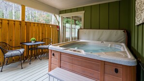 Un jacuzzi en una terraza de madera con sillas y una mesa.