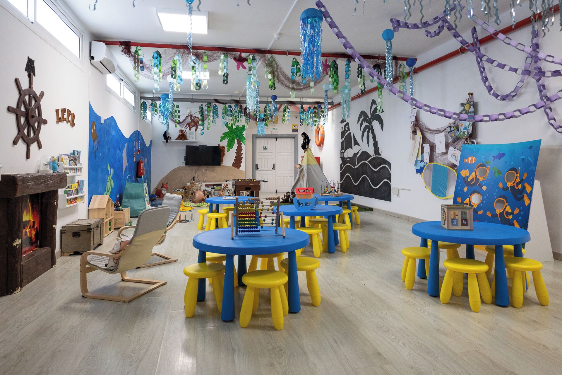Ein Kinderspielzimmer mit runden Tischen und Hocker, Lernspielzeug und Wanddekorationen.