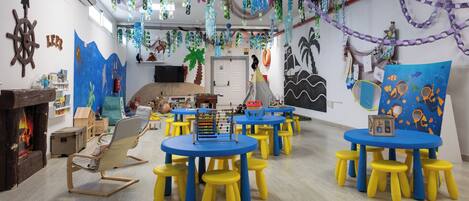 Ein Kinderspielzimmer mit runden Tischen und Hocker, Lernspielzeug und Wanddekorationen.