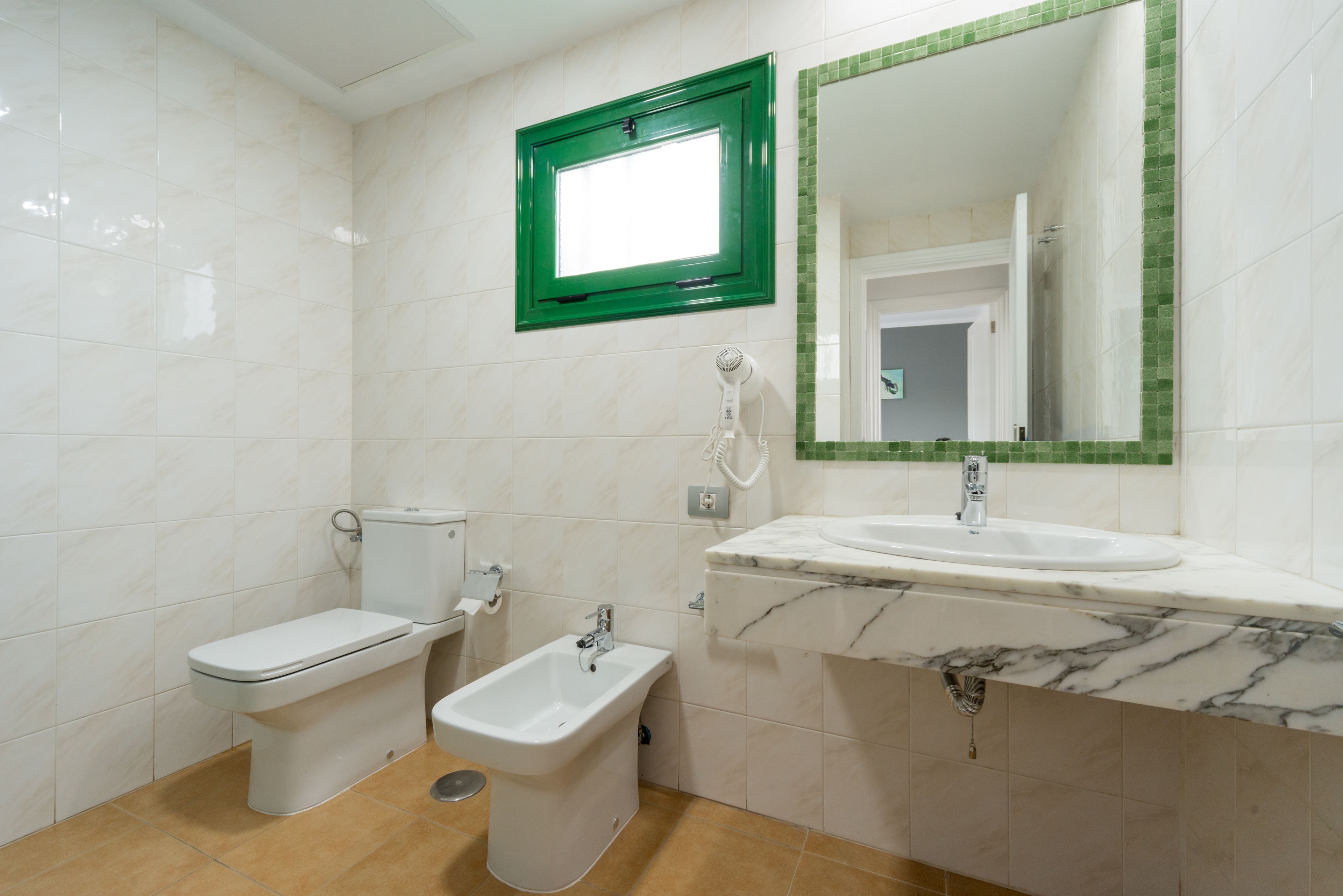 A bathroom with a toilet, bidet, and sink.