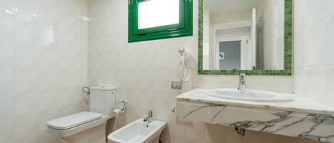 A bathroom with a toilet, bidet, and sink.