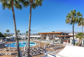 A resort with a pool, sun loungers, palm trees, a large building, and a clear blue sky. - Hyde Park Lane (Tías)