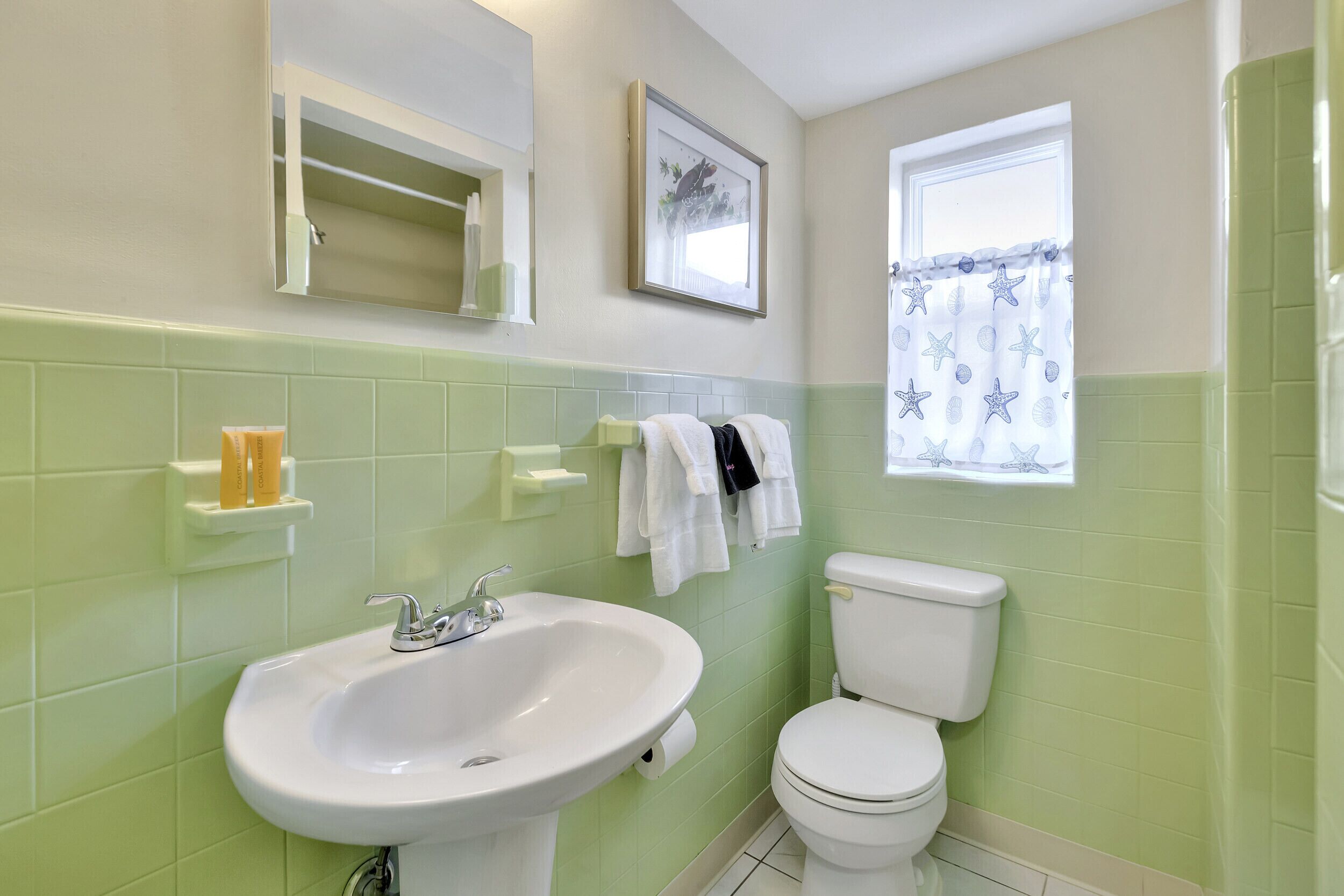 A bathroom with a sink, toilet, and a window with a star-patterned curtain.