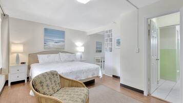 A bedroom with a bed, bedside tables, a chair, and a view of a green outdoor area.
