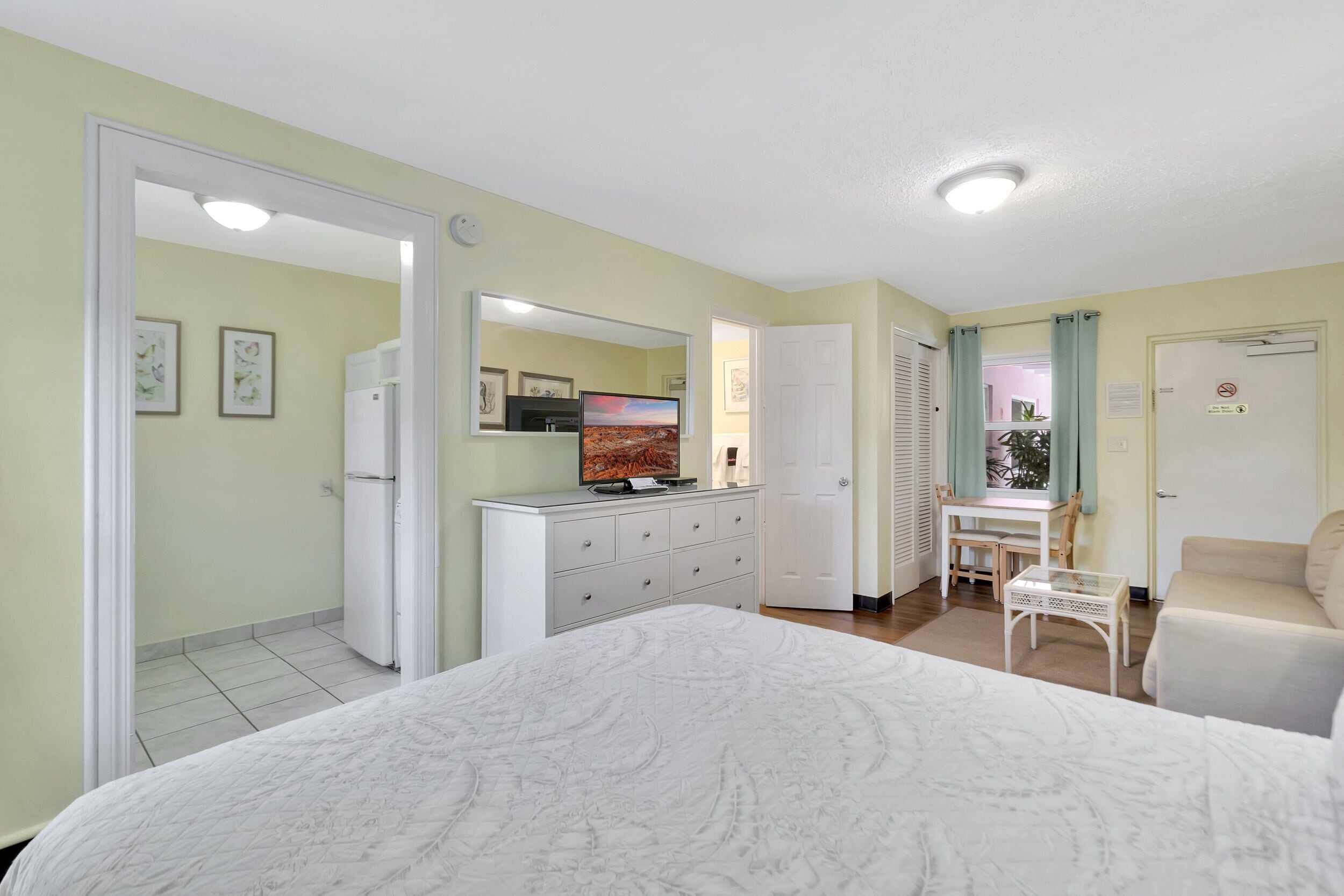 Une chambre à coucher comprenant un lit, une commode, un miroir, un bureau et une chaise.