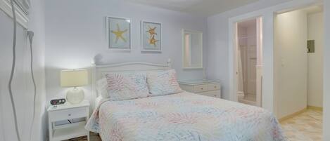 Un dormitorio con cama, mesita de noche, lámpara y dos cuadros con imágenes de estrellas de mar en la pared.