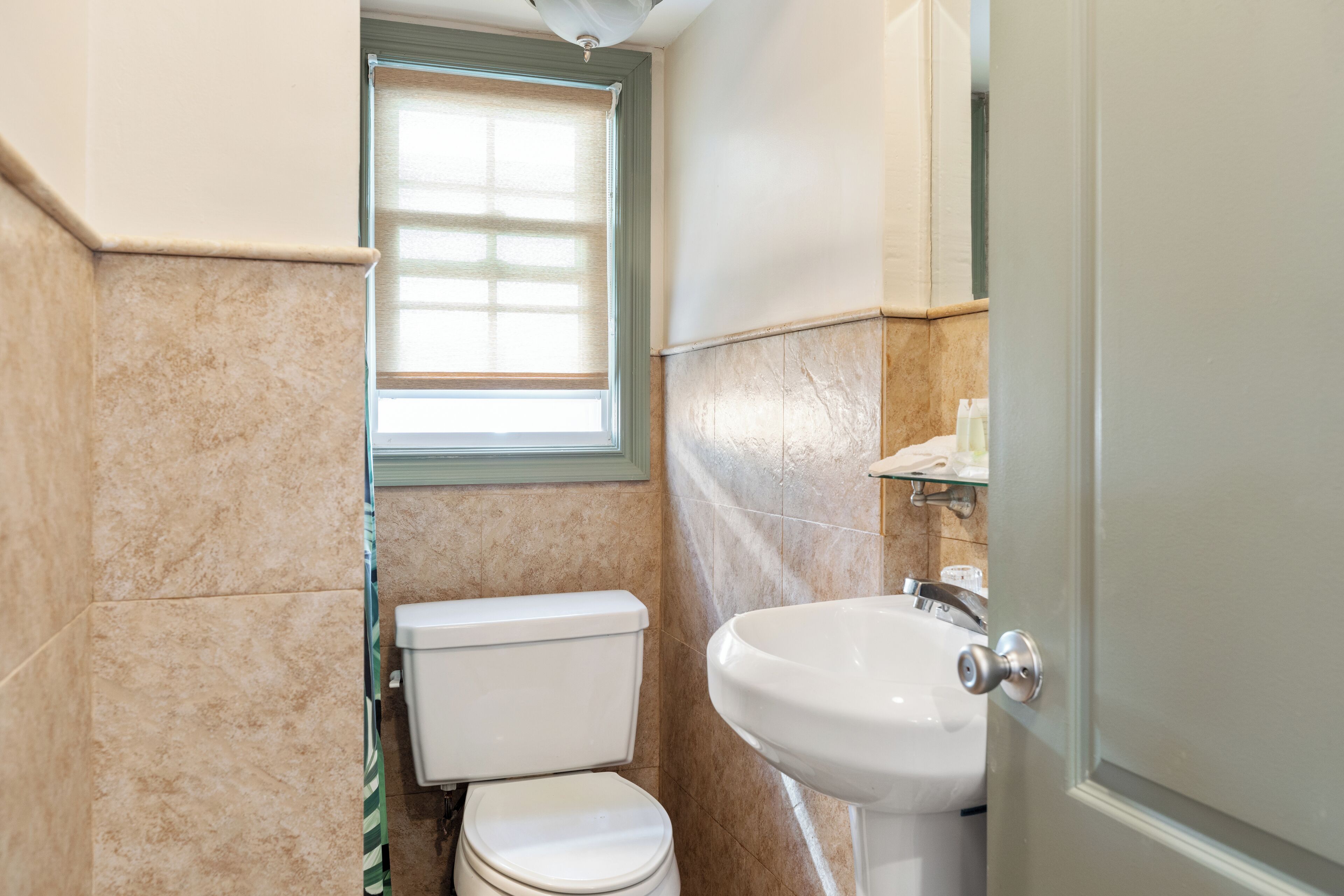 A bathroom with a toilet, sink, and window.