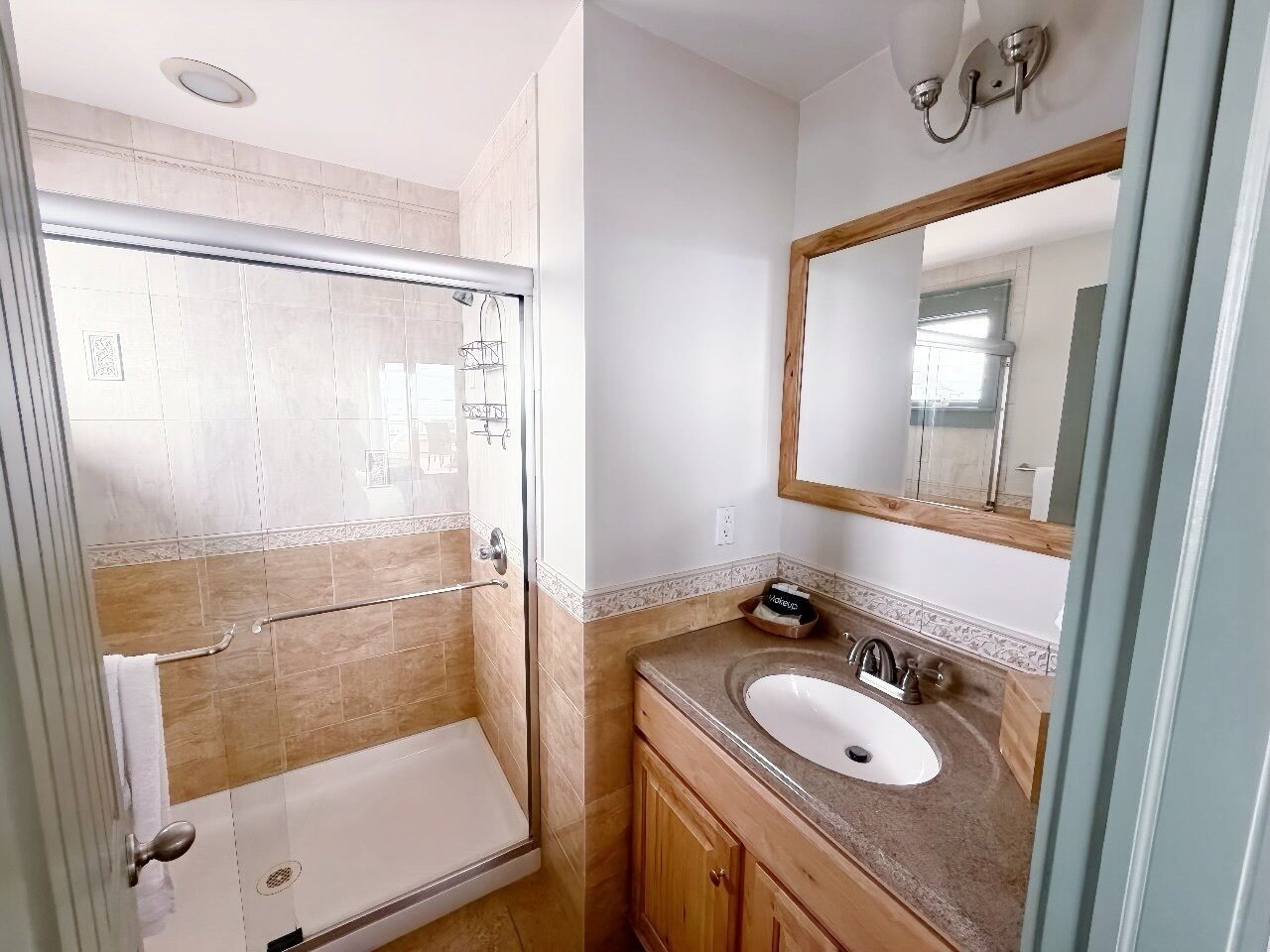 A bathroom with a glass-enclosed shower, a sink with a mirror, and wooden cabinetry.