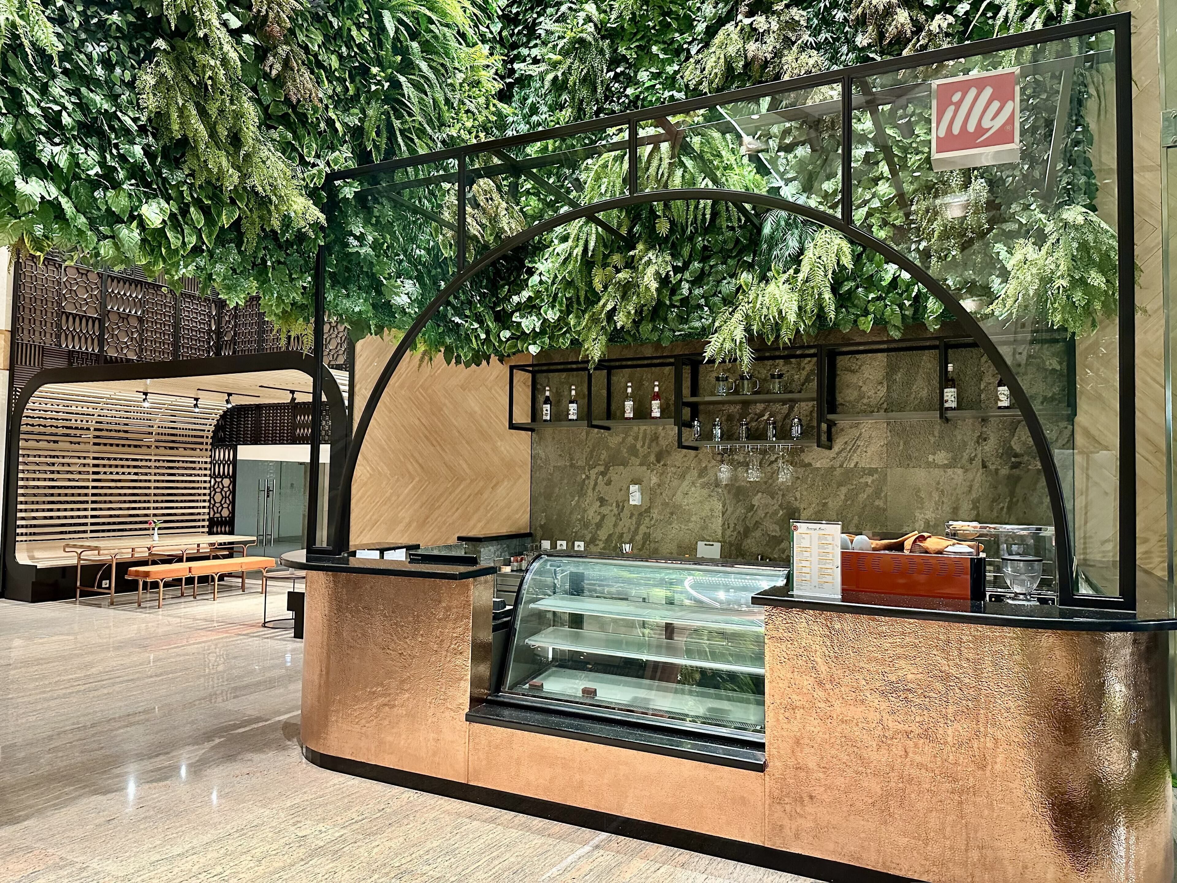 Un café moderne doté d’une vitrine, de bancs en bois et d’un panneau affichant le menu.