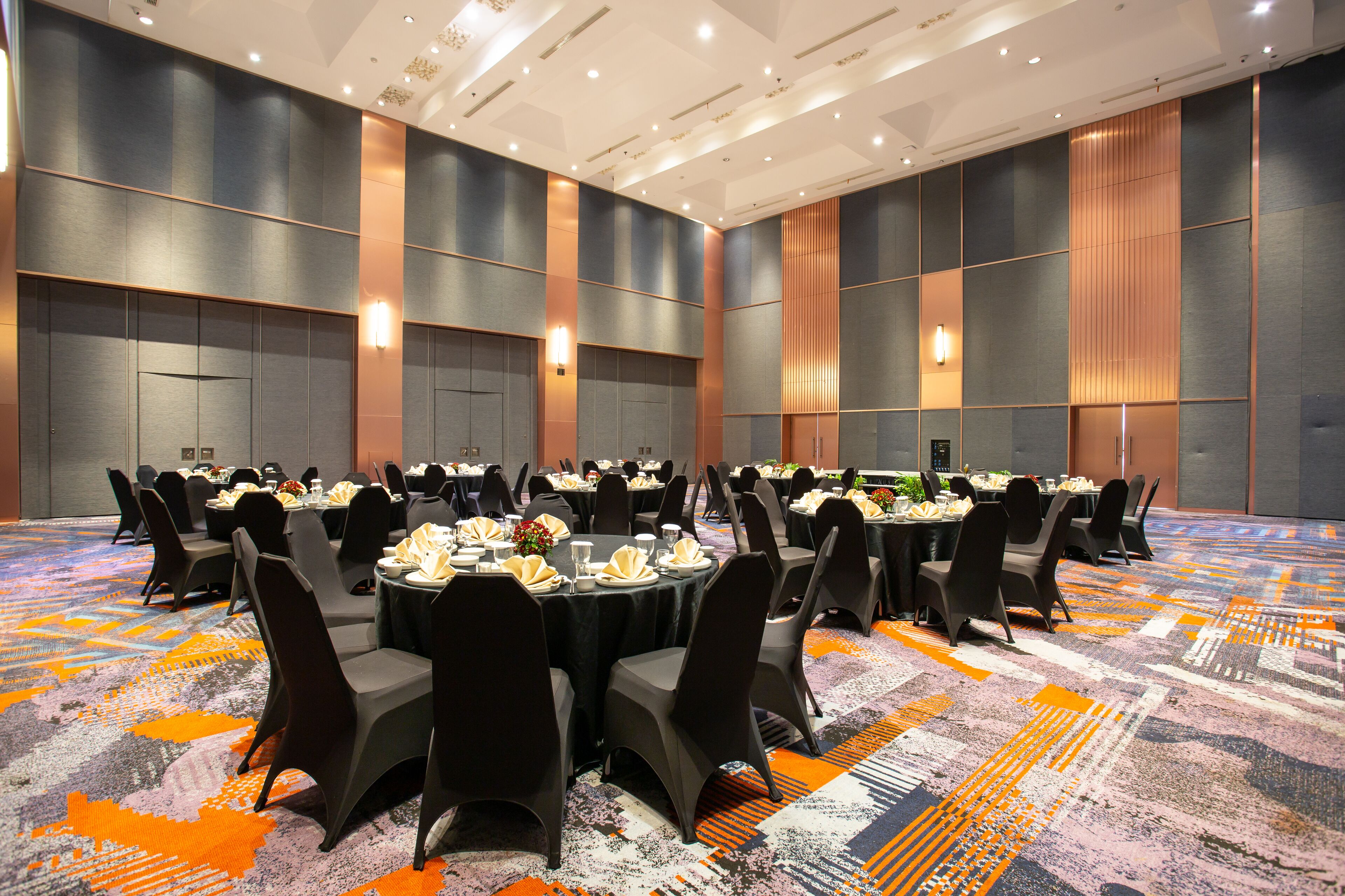 A conference room with round tables, black chairs, and a patterned carpet.