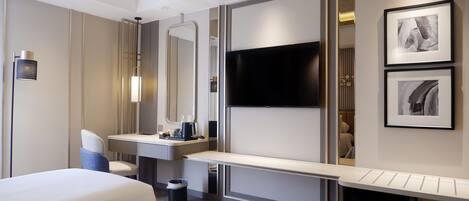 Habitación de hotel moderna con dos camas, un espejo grande, un televisor de pantalla plana, un escritorio y un cubo de basura pequeño.