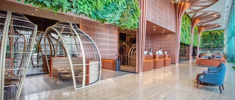 Experience the unique blend of modern design and natural elements in our inviting lobby, featuring a curved reception desk, comfortable seating areas, and a living green wall.