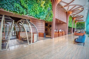 Un vestíbulo moderno con una pared verde, zonas de estar y un mostrador de recepción.