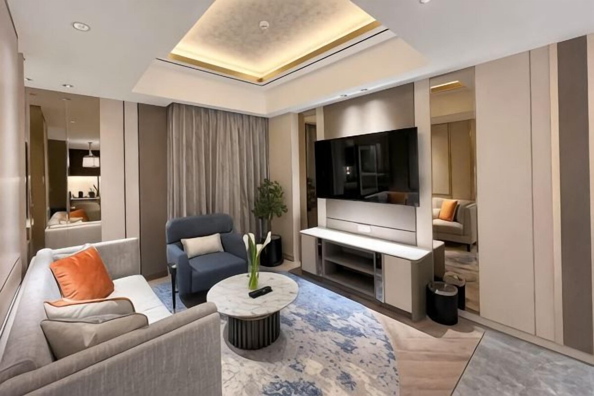 Una sala de estar moderna con sofá, sillón, mesa de centro y televisor de pantalla plana.