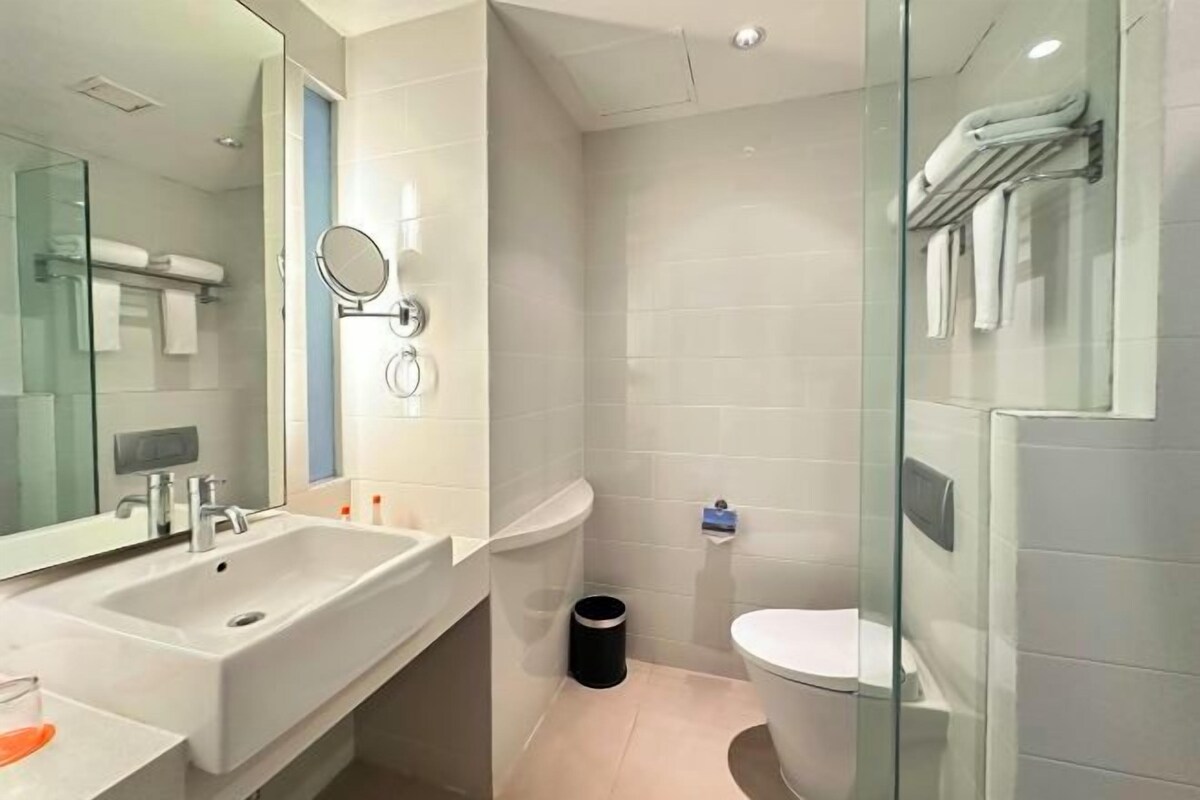 Un baño moderno con un lavabo grande, espejo y cabina de ducha de vidrio.