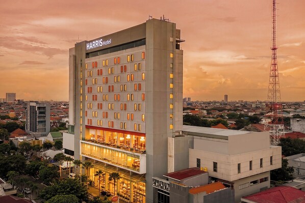 A multi-story hotel with a prominent sign, a ground-level restaurant, and a view of the surrounding cityscape.