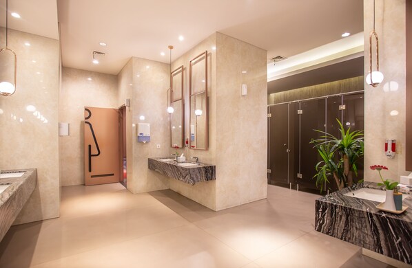 A modern hotel lobby with marble flooring, a central reception desk, and a large mirror.